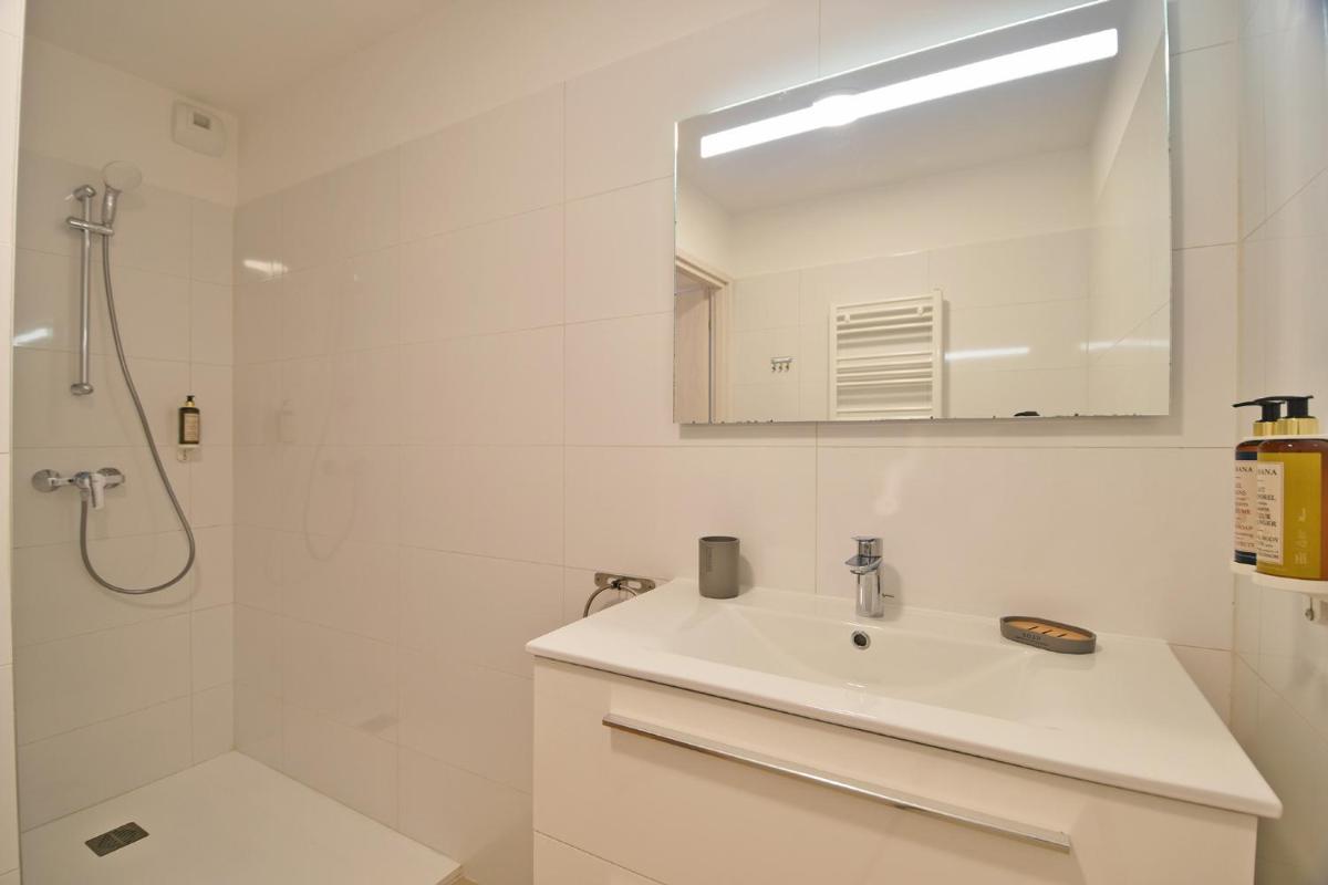 une salle de bain blanche avec un lavabo et une douche dans l'établissement Résidence Saint-Jean, à Saint-Florent