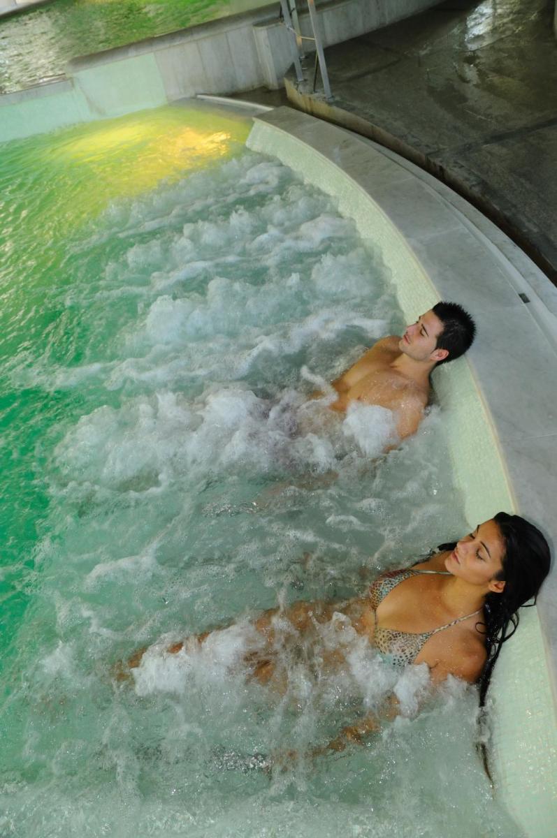 Dos personas nadando en una piscina de agua en Termes Montbrio Hotel & Spa, en Montbrió del Camp