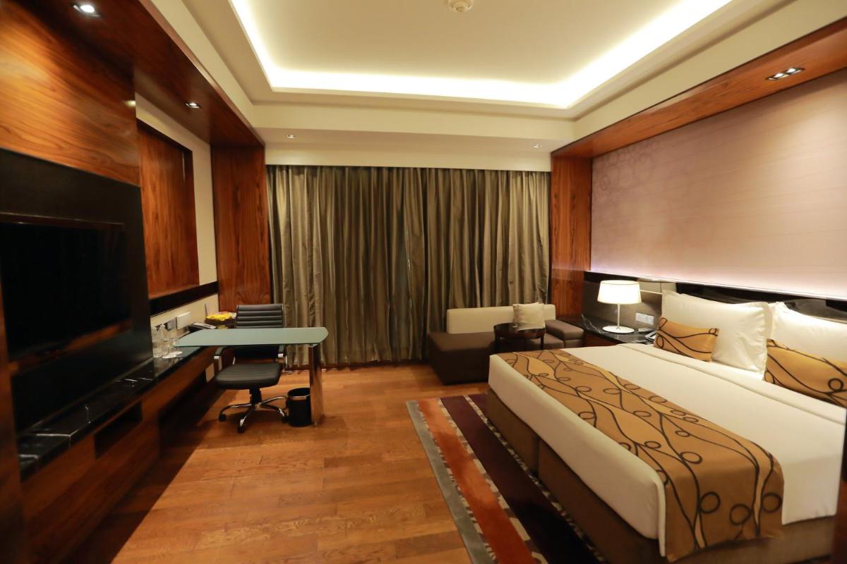 a hotel room with a bed and a desk and a television at Crowne Plaza New Delhi Rohini by IHG in New Delhi a hotel room with a bed and a desk and a television at Crowne Plaza New Delhi Rohini by IHG in New Delhi