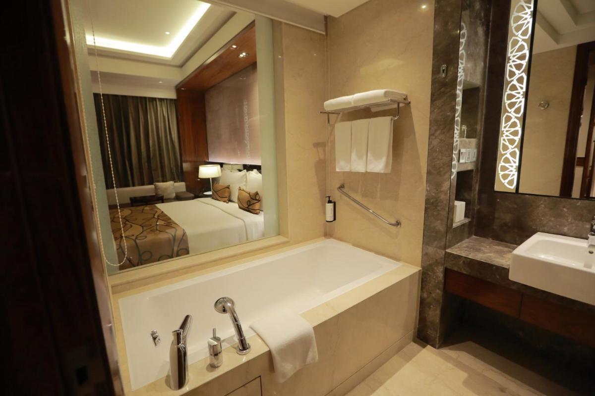 a bathroom with a tub and a sink and a mirror at Crowne Plaza New Delhi Rohini by IHG in New Delhi a bathroom with a tub and a sink and a mirror at Crowne Plaza New Delhi Rohini by IHG in New Delhi