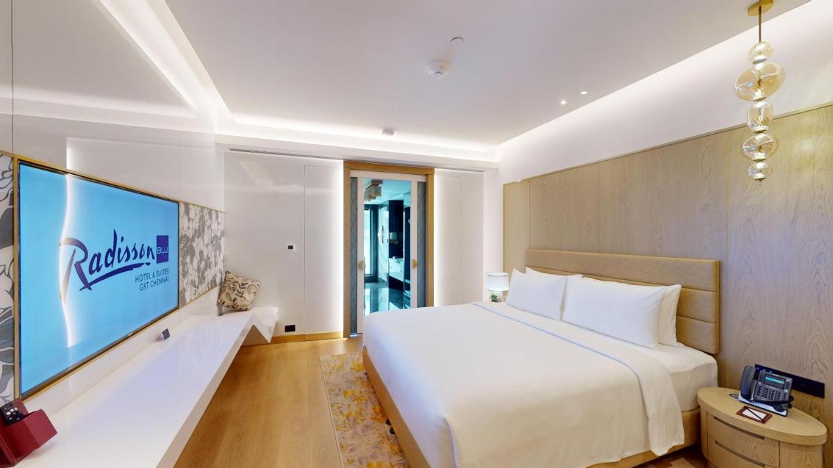 a bedroom with a large white bed and a tv at Radisson Blu Hotel & Suites GRT Chennai in Chennai