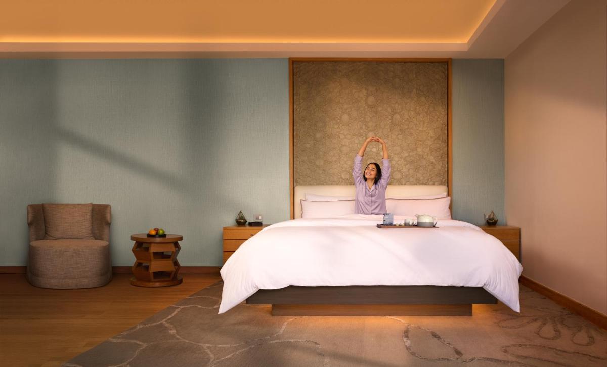 a woman is sitting on a bed in a bedroom at The Westin Resort & Spa Himalayas in Rishīkesh