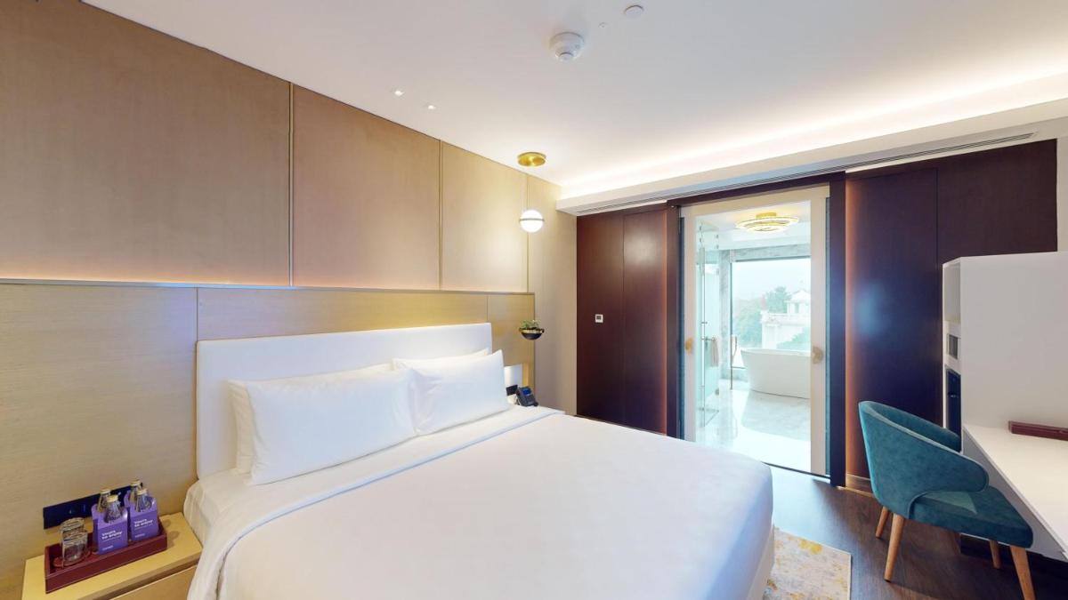 a bedroom with a white bed and a blue chair at Radisson Blu Hotel & Suites GRT Chennai in Chennai