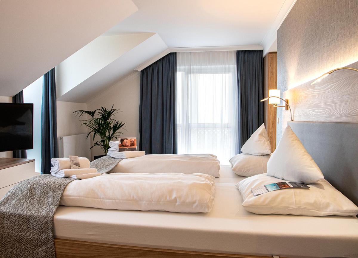 ein Hotelzimmer mit zwei Betten und einem Fenster in der Unterkunft Hotel St. Wolfgang in Bad Griesbach ein Hotelzimmer mit zwei Betten und einem Fenster in der Unterkunft Hotel St. Wolfgang in Bad Griesbach