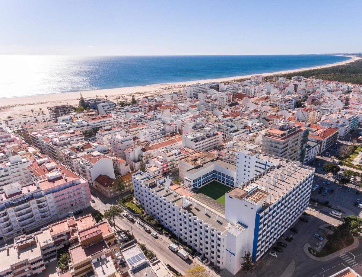 uma vista aérea de uma cidade e da praia em Hotel Navegadores em Monte Gordo