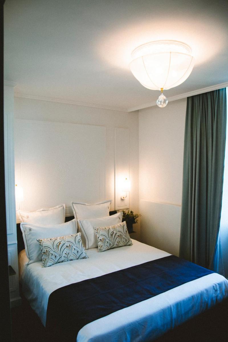 une chambre avec un grand lit avec des oreillers bleus et blancs dans l'établissement Le Berceau de La Source, à Bagnères-de-Bigorre