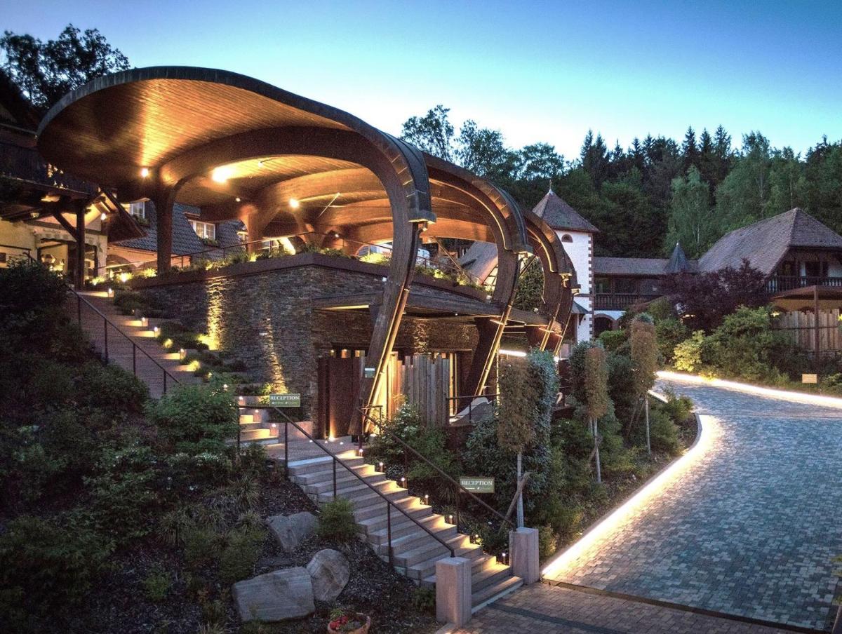 un bâtiment avec un toit incurvé et des lumières sur lui dans l'établissement LA CHENEAUDIÈRE - Hôtel Spa - Relais & Châteaux - Restaurant étoilé, à Colroy-la-Roche