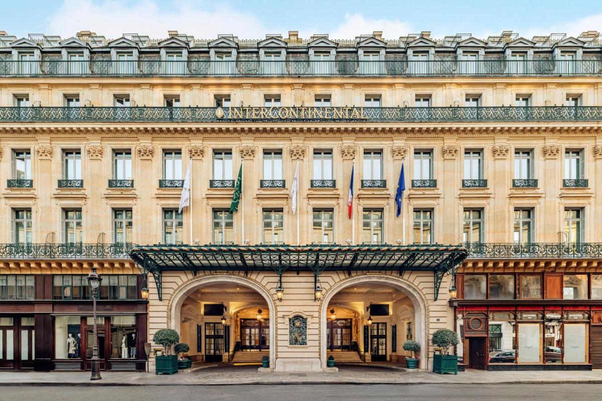 un grand bâtiment avec deux drapeaux devant dans l'établissement InterContinental Paris Le Grand by IHG, à Paris