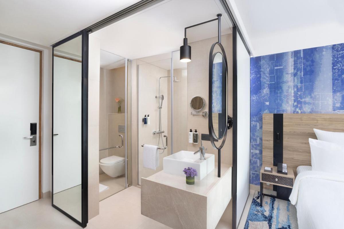 a hotel room with a bathroom with a toilet and a sink at Novotel New Delhi City Centre in New Delhi a hotel room with a bathroom with a toilet and a sink at Novotel New Delhi City Centre in New Delhi
