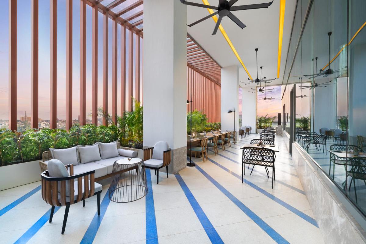 a lobby with tables and chairs and windows at Novotel New Delhi City Centre in New Delhi a lobby with tables and chairs and windows at Novotel New Delhi City Centre in New Delhi