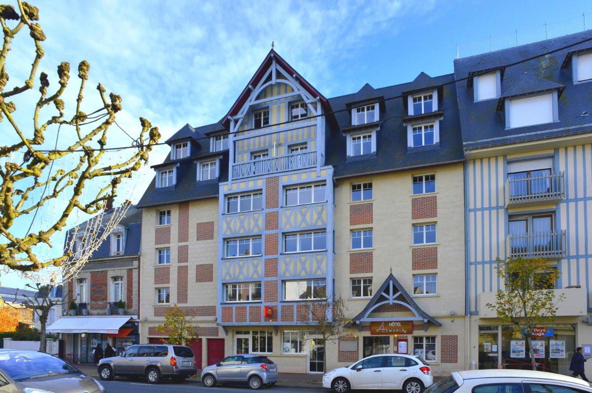 un grand bâtiment avec des voitures garées devant dans l'établissement Almoria Hôtel & SPA, à Deauville