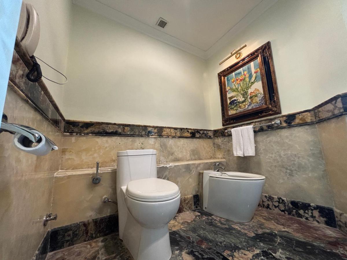 a bathroom with a toilet and a painting on the wall at Le Royal Meridien Chennai in Chennai