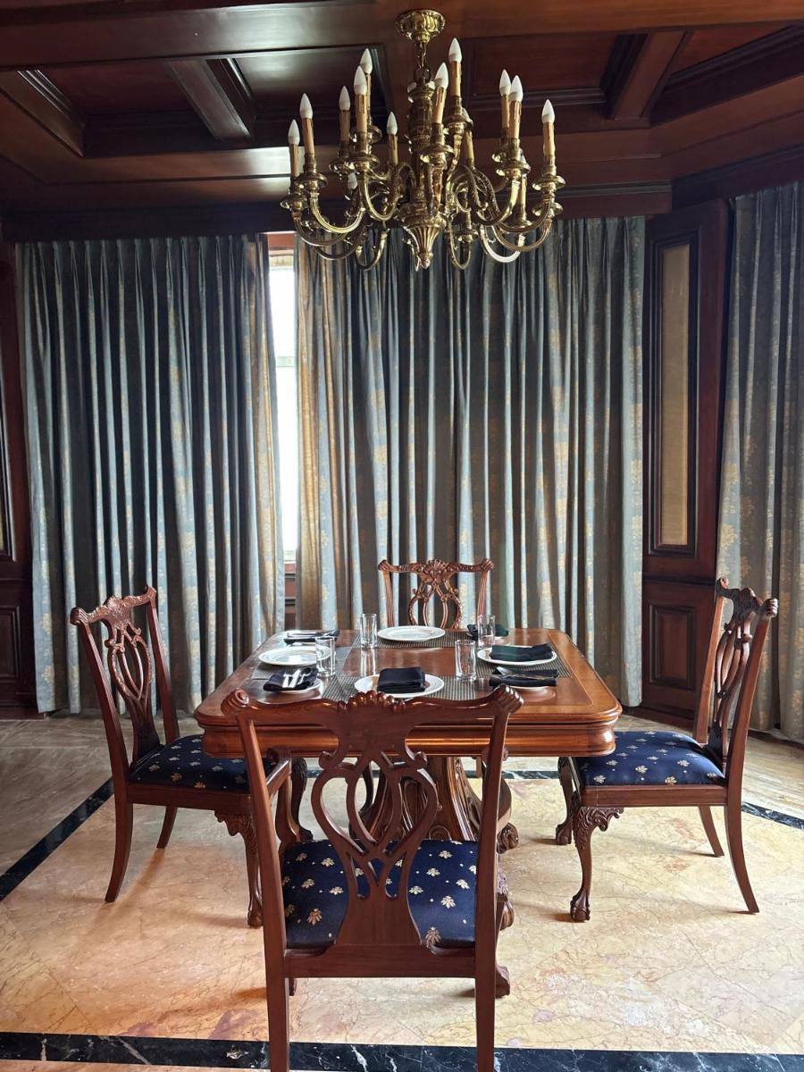 a dining room with a table and chairs and a chandelier at Le Royal Meridien Chennai in Chennai
