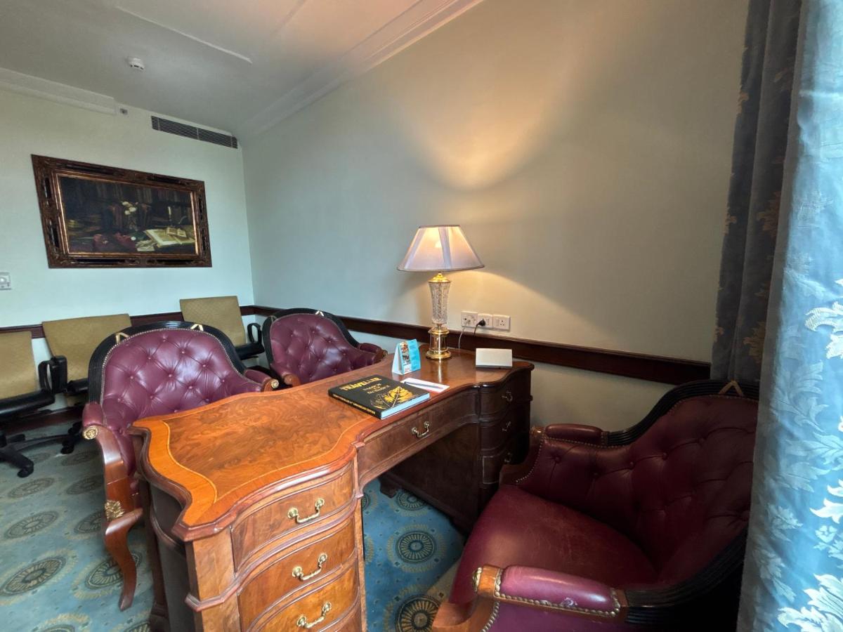 a room with a desk and chairs and a lamp at Le Royal Meridien Chennai in Chennai