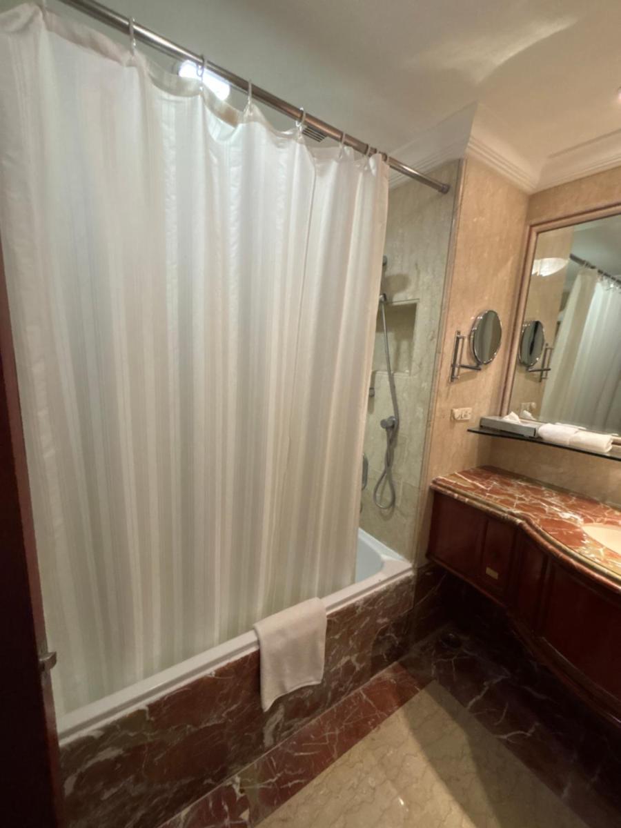 a bathroom with a shower with a white shower curtain at Le Royal Meridien Chennai in Chennai