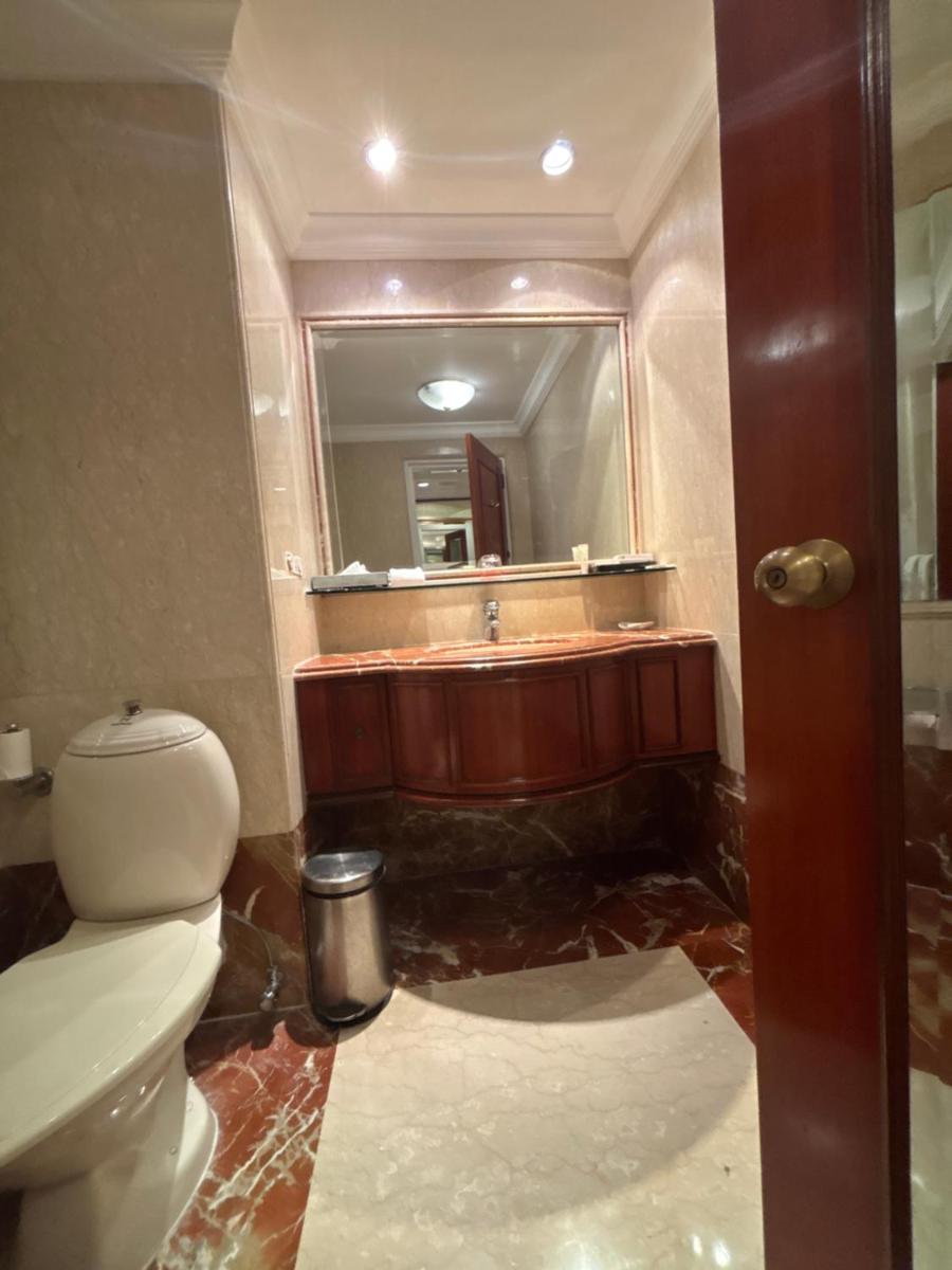 a bathroom with a toilet and a sink and a mirror at Le Royal Meridien Chennai in Chennai