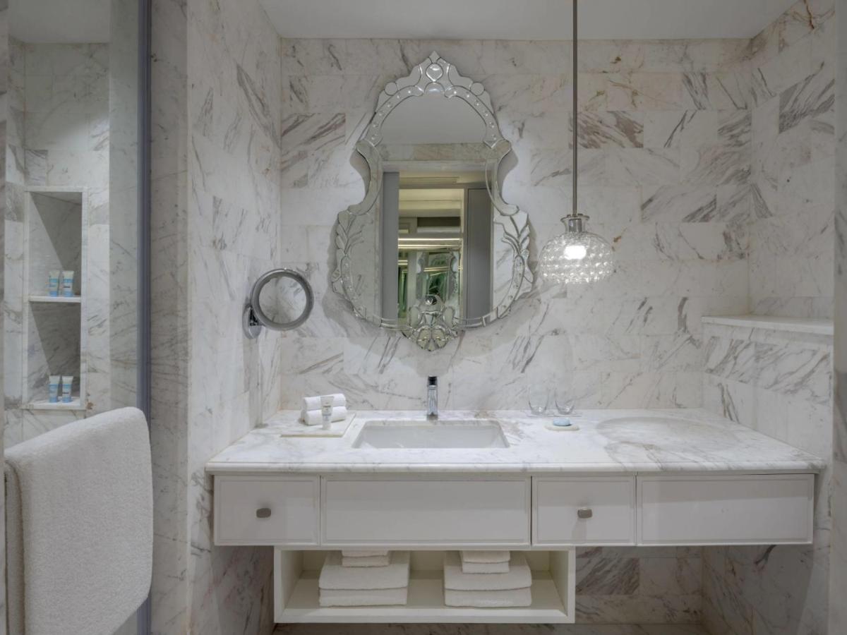 a white bathroom with a sink and a mirror at ITC Windsor, a Luxury Collection Hotel, Bengaluru in Bengaluru a white bathroom with a sink and a mirror at ITC Windsor, a Luxury Collection Hotel, Bengaluru in Bengaluru