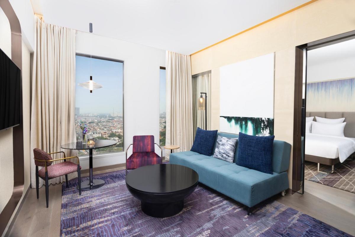 a living room with a blue couch and a room with a view at Novotel New Delhi City Centre in New Delhi a living room with a blue couch and a room with a view at Novotel New Delhi City Centre in New Delhi