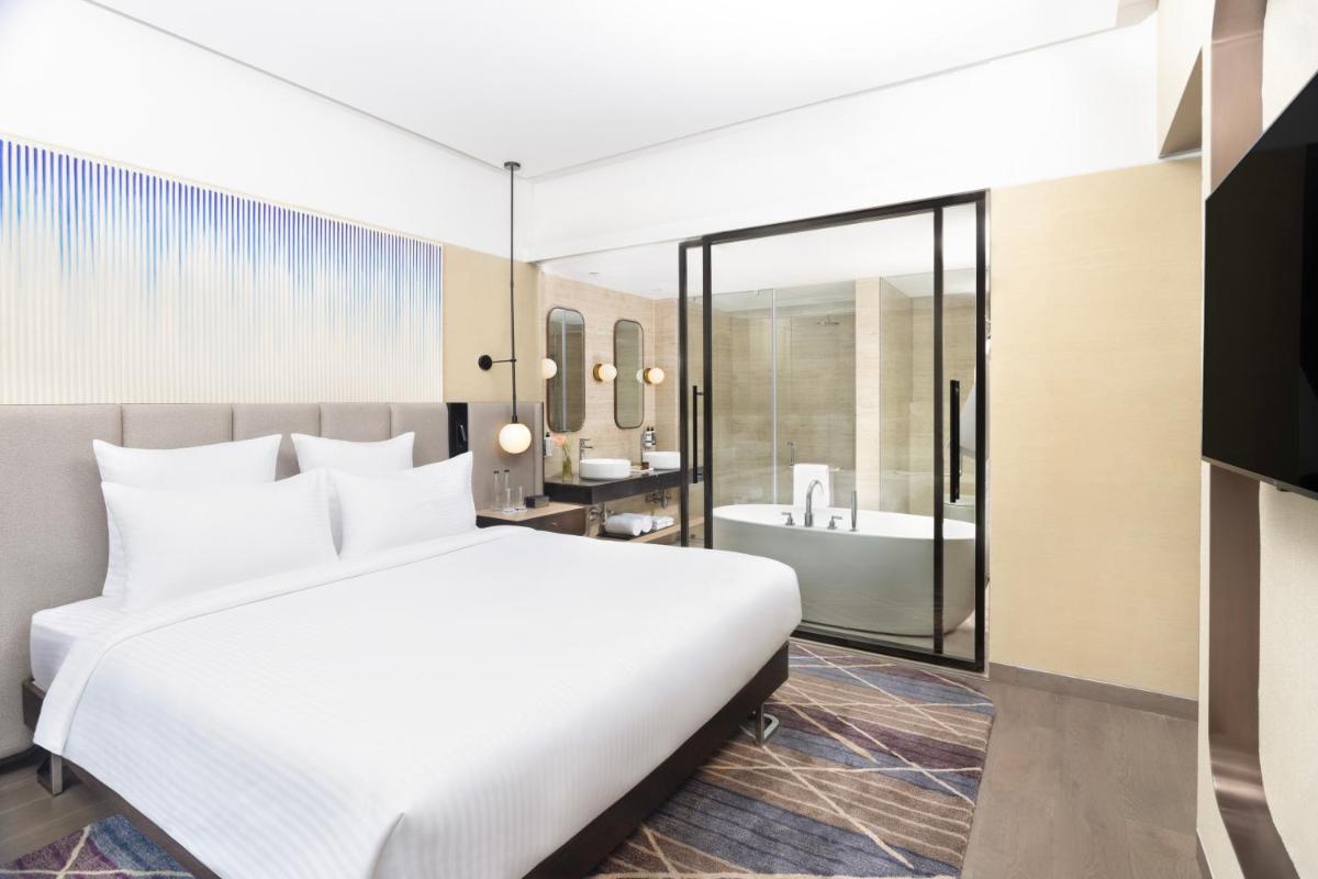 a bedroom with a large bed and a bathroom at Novotel New Delhi City Centre in New Delhi a bedroom with a large bed and a bathroom at Novotel New Delhi City Centre in New Delhi