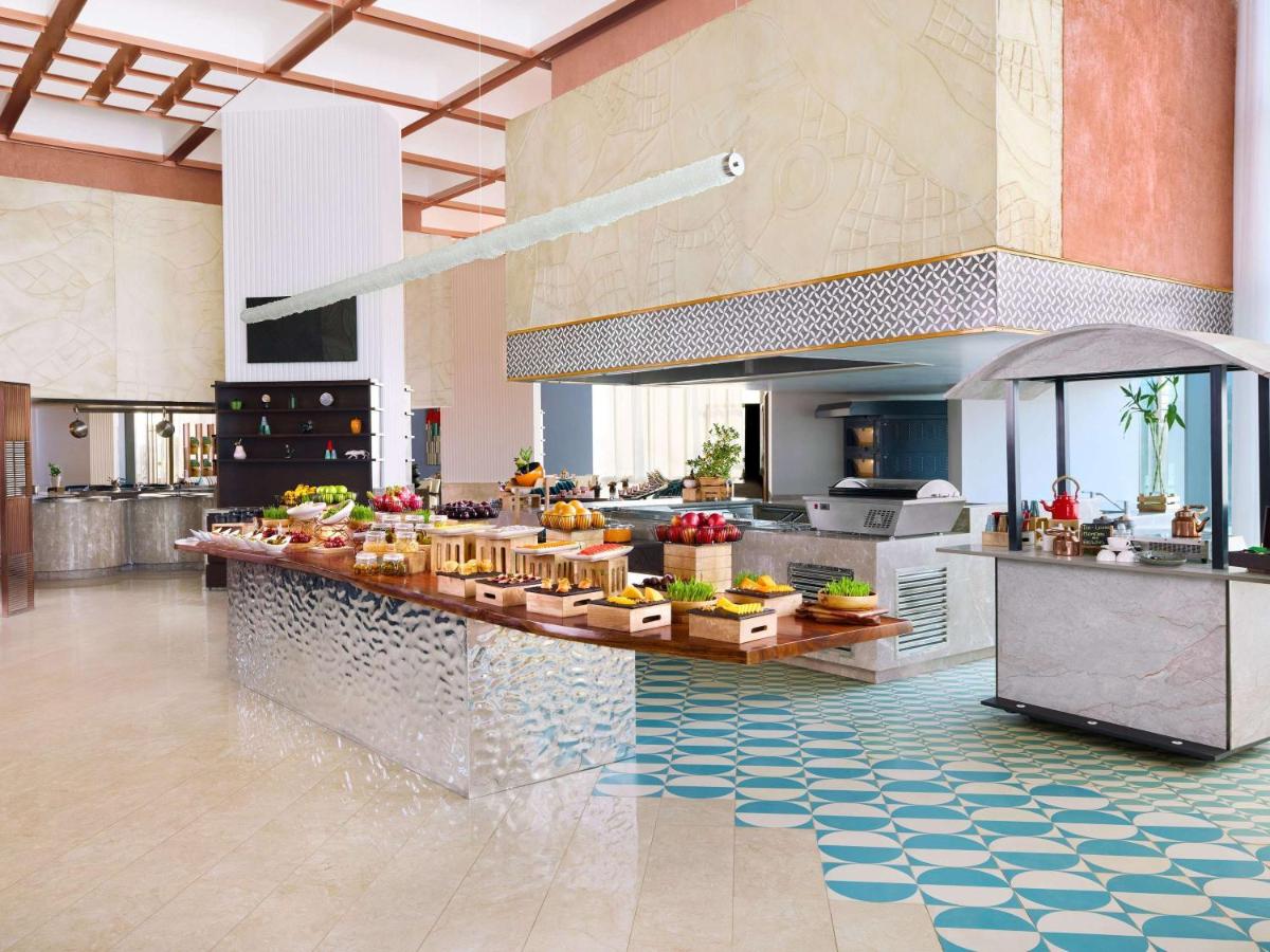 a kitchen with a counter with food on it at Novotel New Delhi City Centre in New Delhi a kitchen with a counter with food on it at Novotel New Delhi City Centre in New Delhi