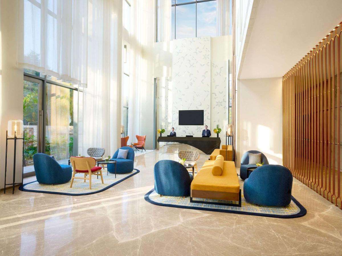 a lobby with chairs and a table and a television at Novotel New Delhi City Centre in New Delhi a lobby with chairs and a table and a television at Novotel New Delhi City Centre in New Delhi