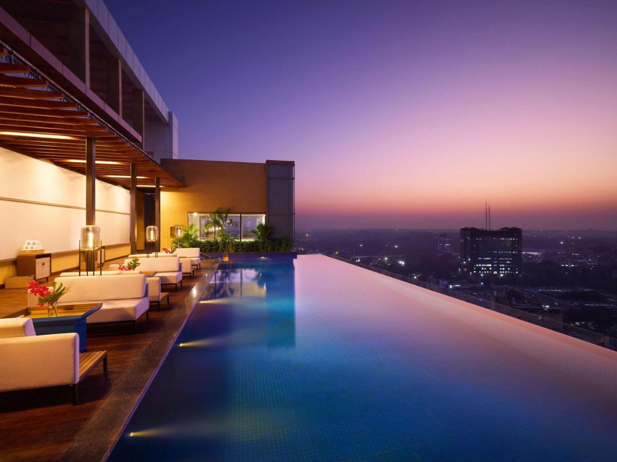 a swimming pool in a building with a view at Novotel New Delhi City Centre in New Delhi a swimming pool in a building with a view at Novotel New Delhi City Centre in New Delhi