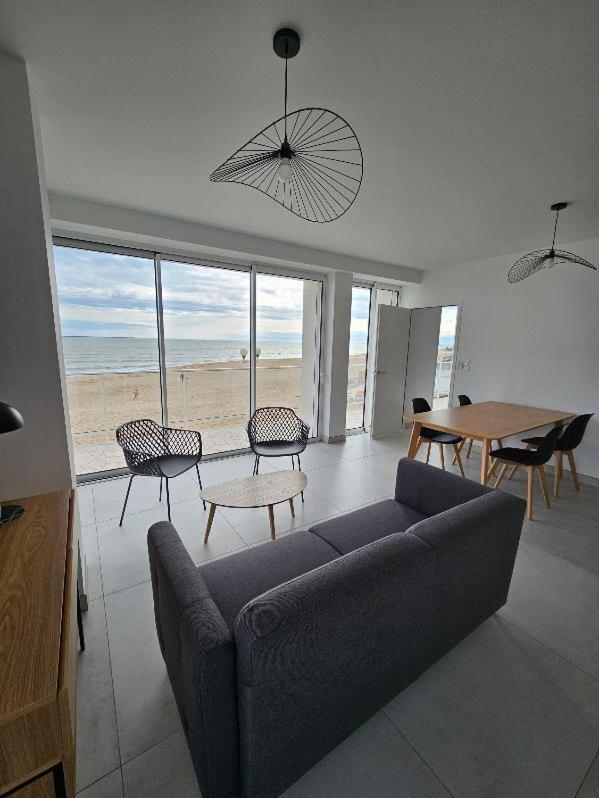 un salon avec un canapé, une table et des chaises dans l'établissement Hotel Les Dunes, à La Tranche-sur-Mer