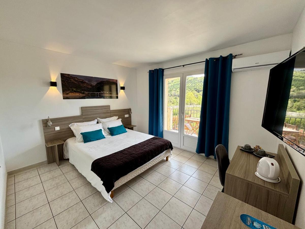 une chambre avec un lit avec des oreillers bleus et une fenêtre dans l'établissement Hôtel Spa L'Ermitage, aux Salles-sur-Verdon