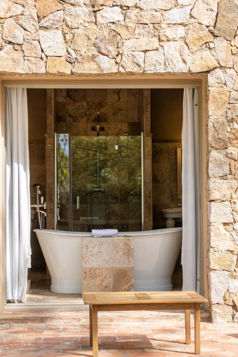 une grande salle de bain avec une baignoire dans un mur en pierre dans l'établissement La Signoria & Spa, à Calvi