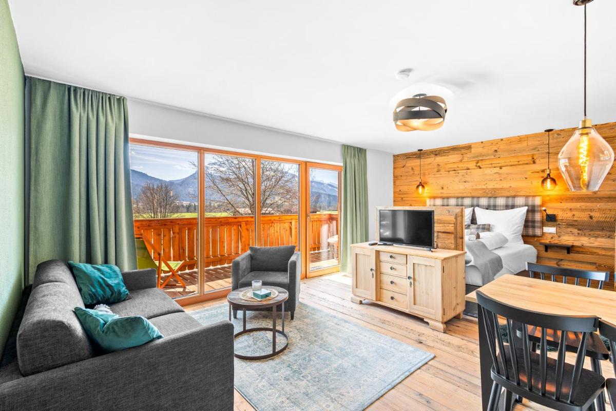 ein Wohnzimmer mit einer Couch und einem Tisch und einem Fernseher in der Unterkunft Soho Mountain Chalet - Pool und Sauna in Reit im Winkl + 37 Fotos