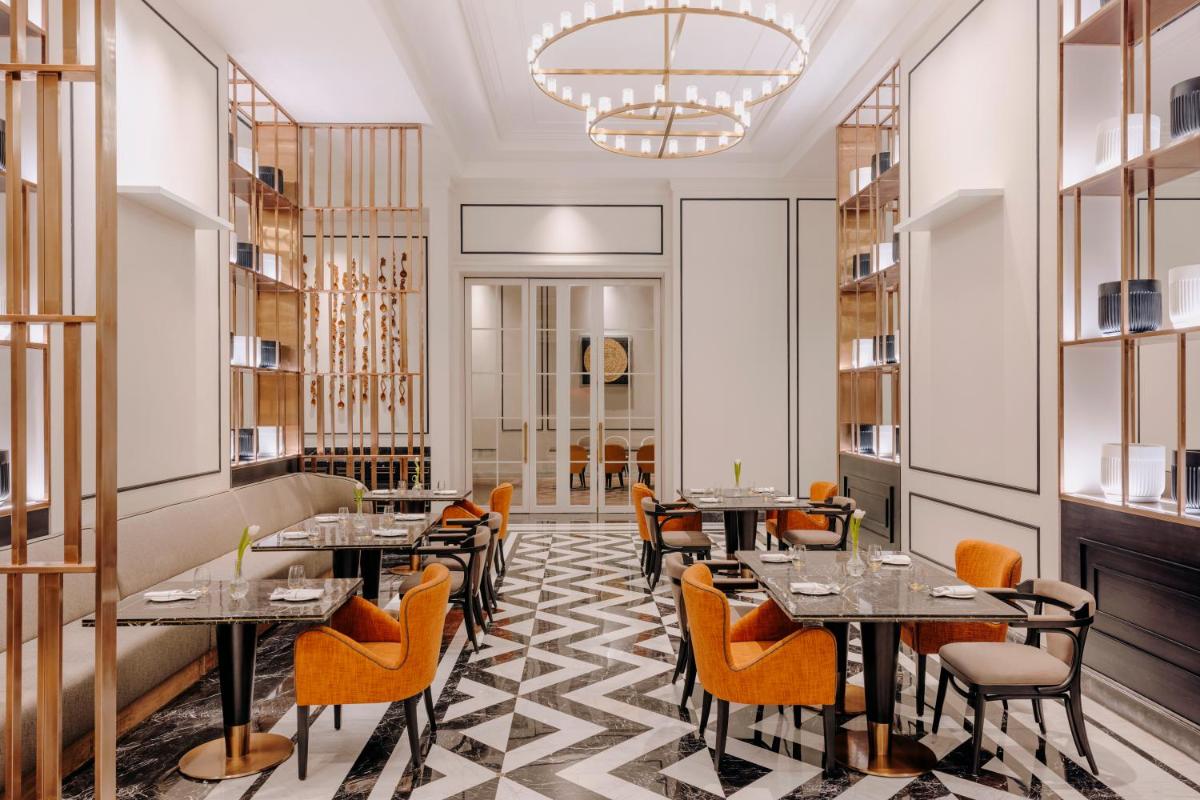 a restaurant with tables and chairs and a chandelier at Fairmont Mumbai in Mumbai
