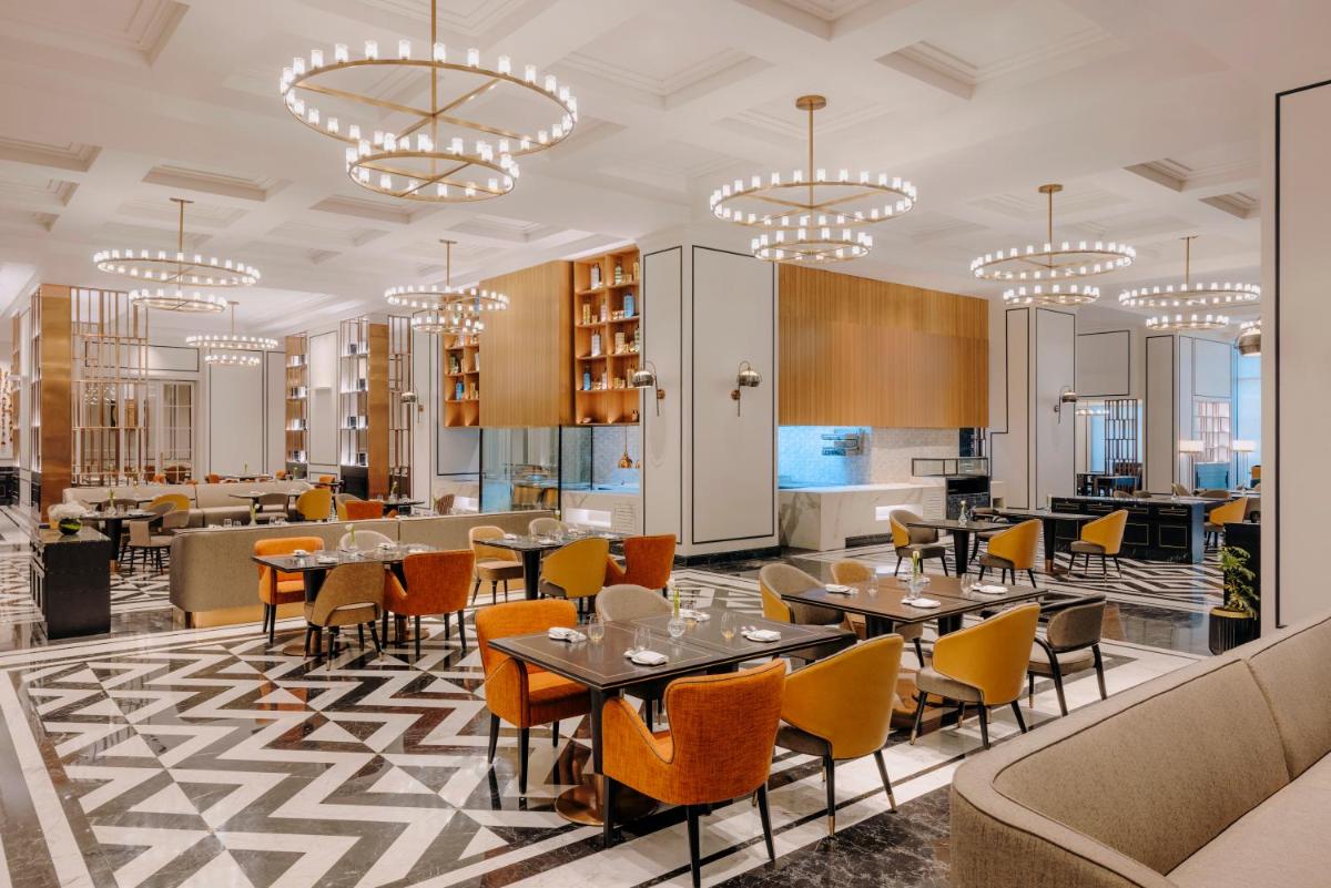 a dining room with tables and chairs and chandeliers at Fairmont Mumbai in Mumbai
