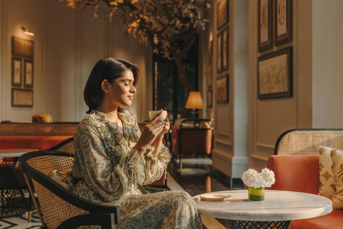 a woman sitting in a chair holding a cup at Fairmont Mumbai in Mumbai