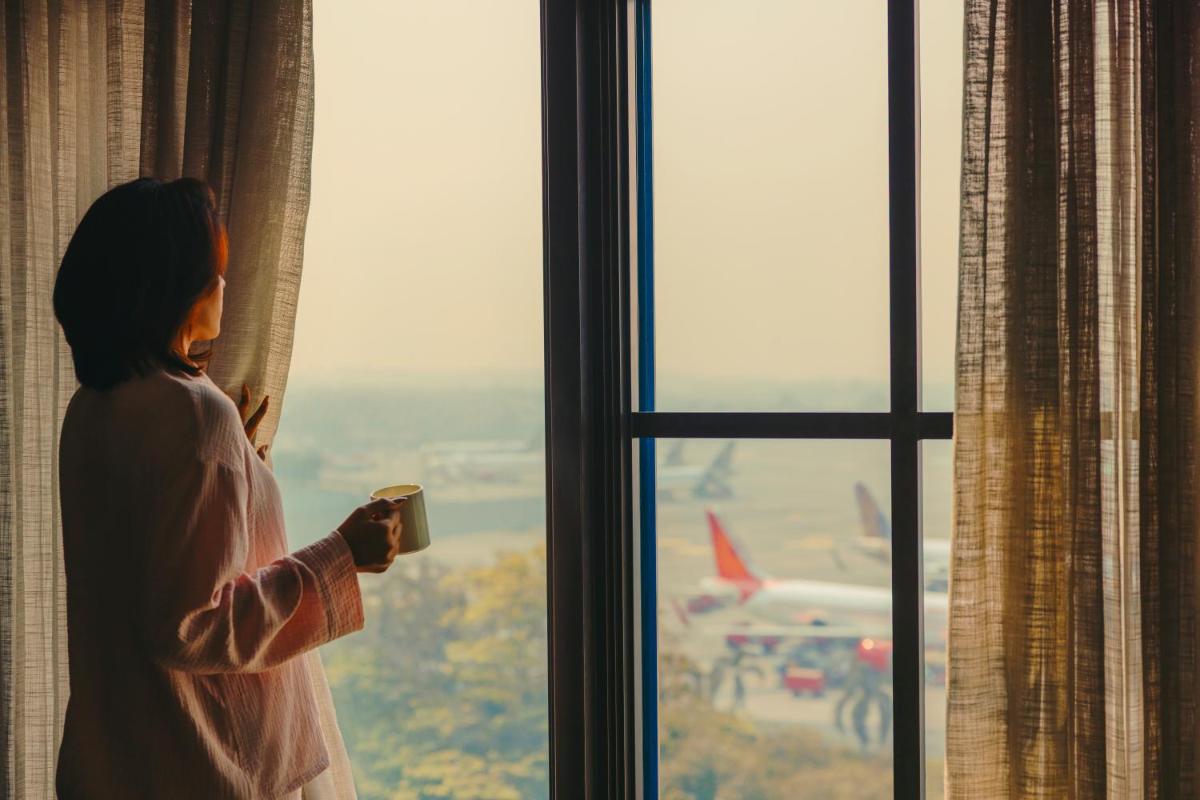 a woman looking out a window at an airplane at Fairmont Mumbai in Mumbai