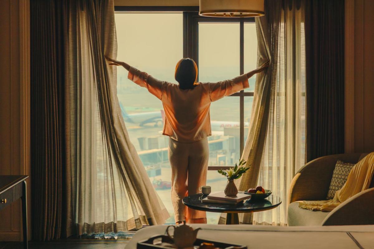 a man looking out the window of a hotel room at Fairmont Mumbai in Mumbai