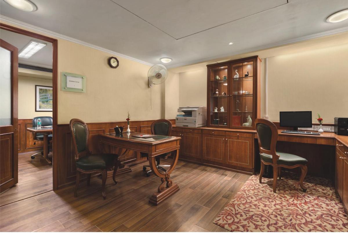 an office with a desk with chairs and a computer at Ramada Plaza By Wyndham Palm Grove in Mumbai