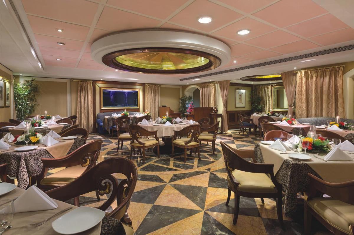 a restaurant with tables and chairs and a chandelier at Ramada Plaza By Wyndham Palm Grove in Mumbai