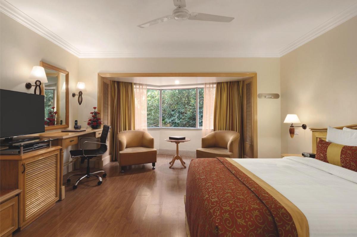 a hotel room with a bed and a desk at Ramada Plaza By Wyndham Palm Grove in Mumbai