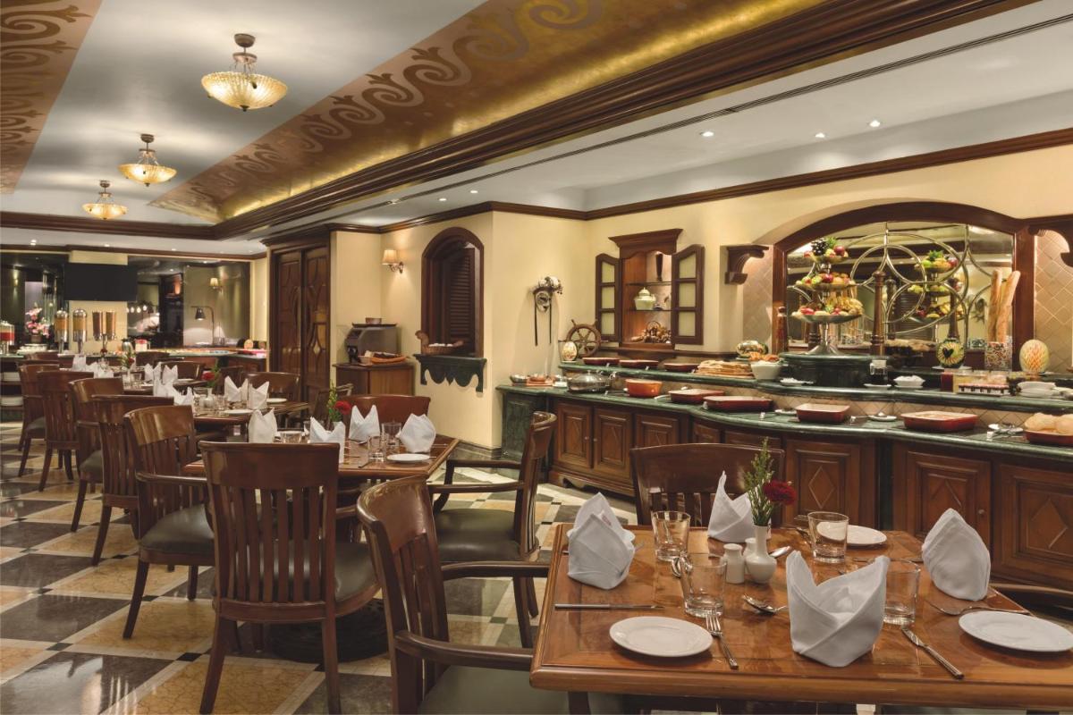 a restaurant with wooden tables and chairs and a bar at Ramada Plaza By Wyndham Palm Grove in Mumbai