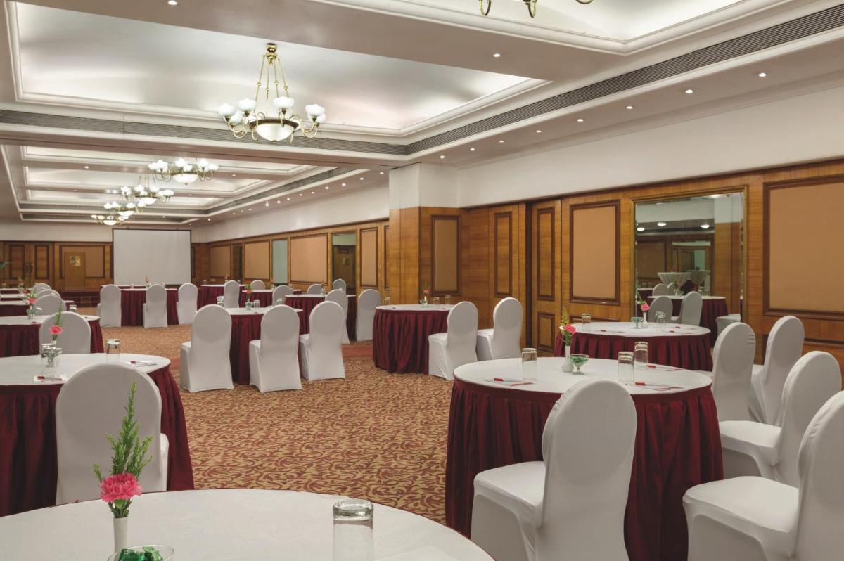 a conference room with tables and chairs and a chandelier at Ramada Plaza By Wyndham Palm Grove in Mumbai