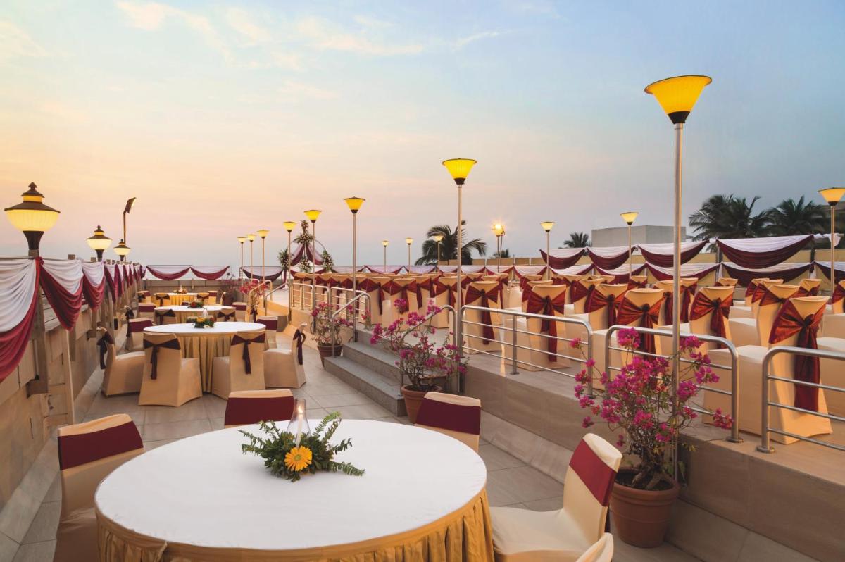 a view of a rooftop patio with tables and chairs at Ramada Plaza By Wyndham Palm Grove in Mumbai +52 photos