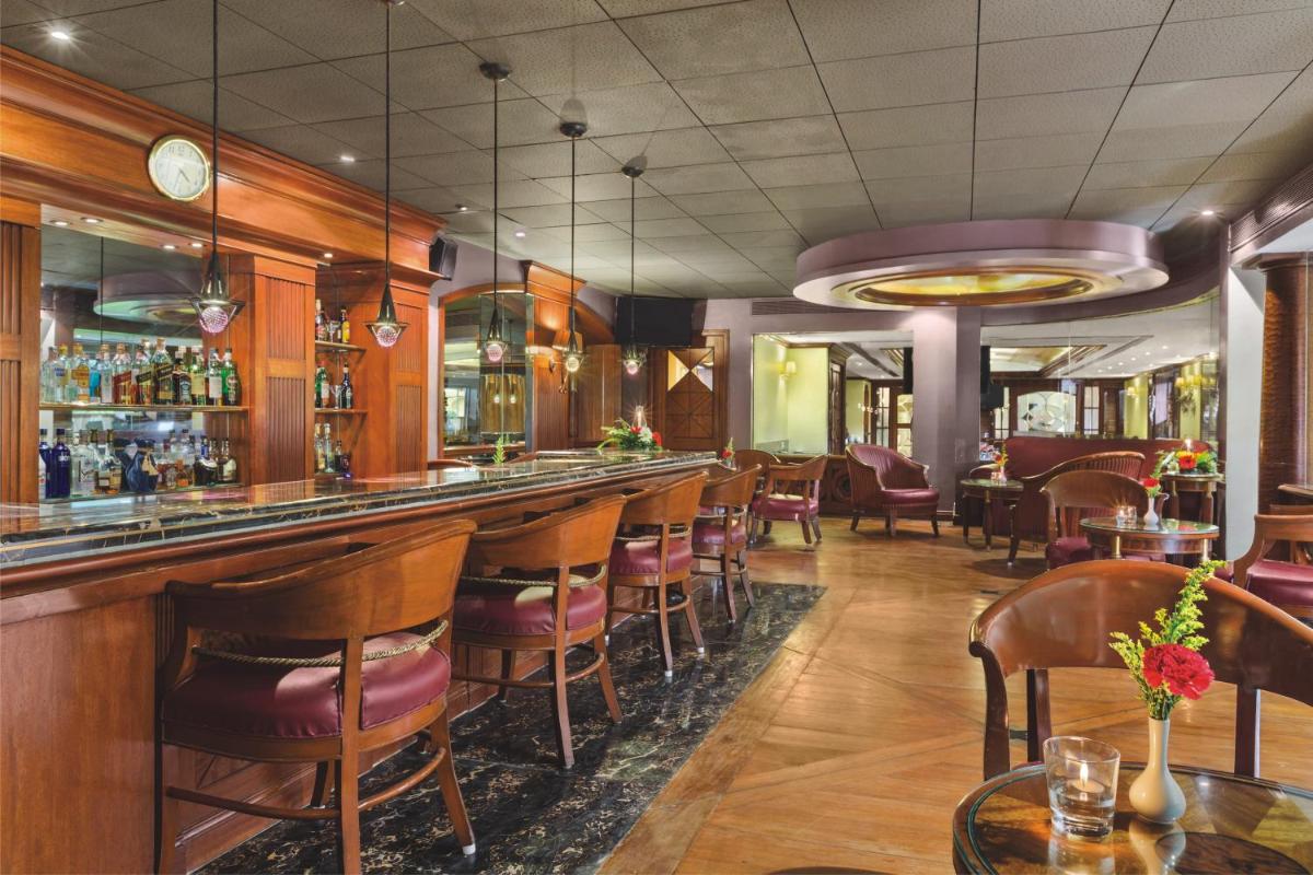 a restaurant with a bar with chairs and tables at Ramada Plaza By Wyndham Palm Grove in Mumbai