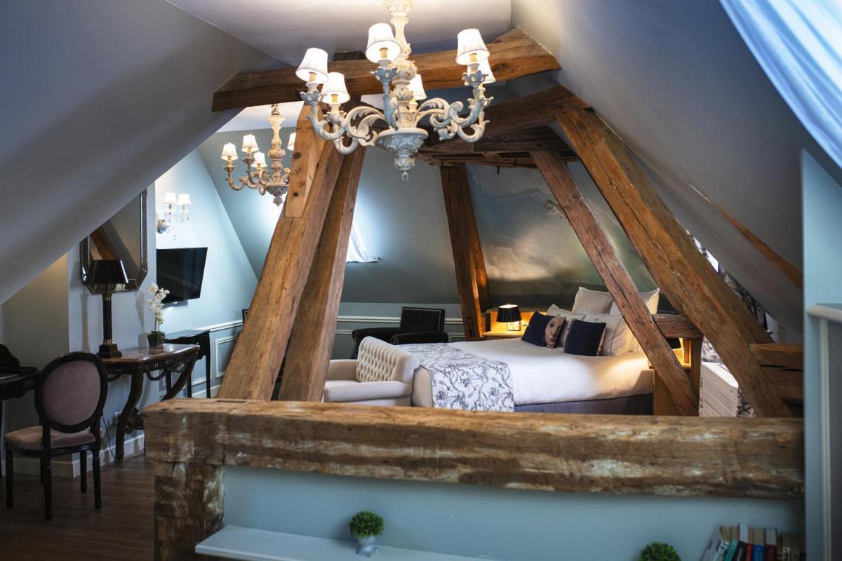 une chambre avec un lit et un lustre dans l'établissement Hotel & Spa Le Grand Monarque, BW Premier Collection, à Chartres