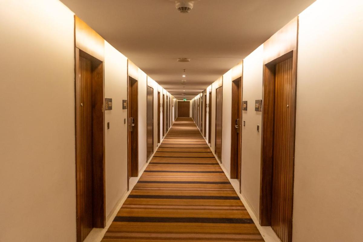 a hallway with wooden doors and a long corridor at Holiday Inn Kolkata Airport by IHG in Kolkata