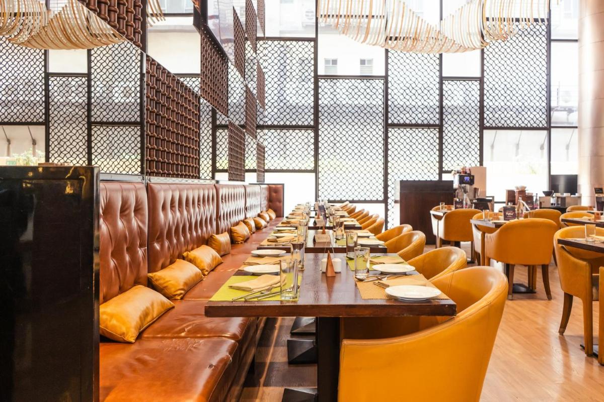a dining room with a long table and yellow chairs at Holiday Inn Kolkata Airport by IHG in Kolkata