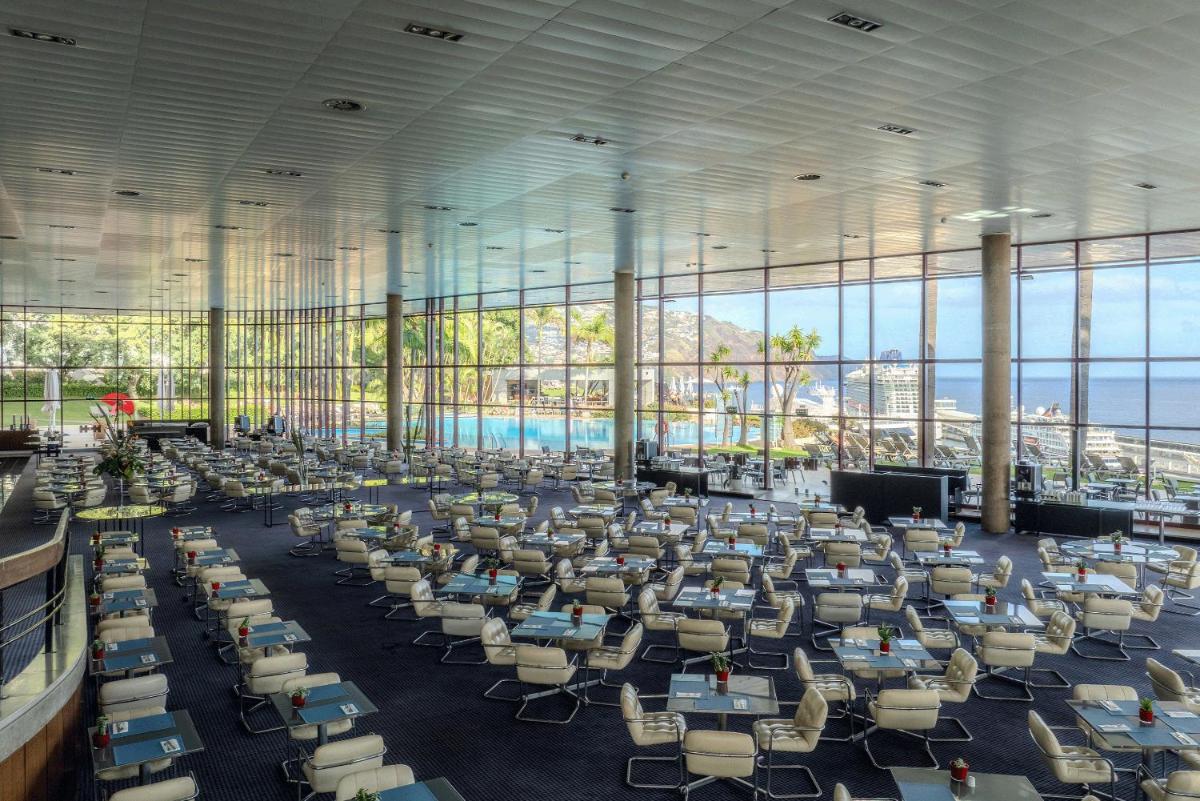 um quarto amplo com cadeiras, mesas e janelas em Pestana Casino Park Hotel & Casino no Funchal