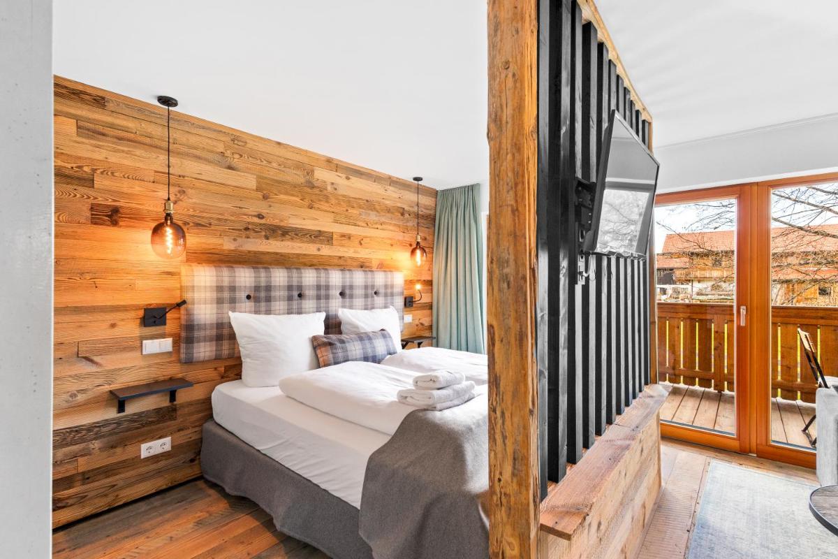 ein Schlafzimmer mit einem Bett mit einer Holzwand in der Unterkunft Soho Mountain Chalet - Pool und Sauna in Reit im Winkl