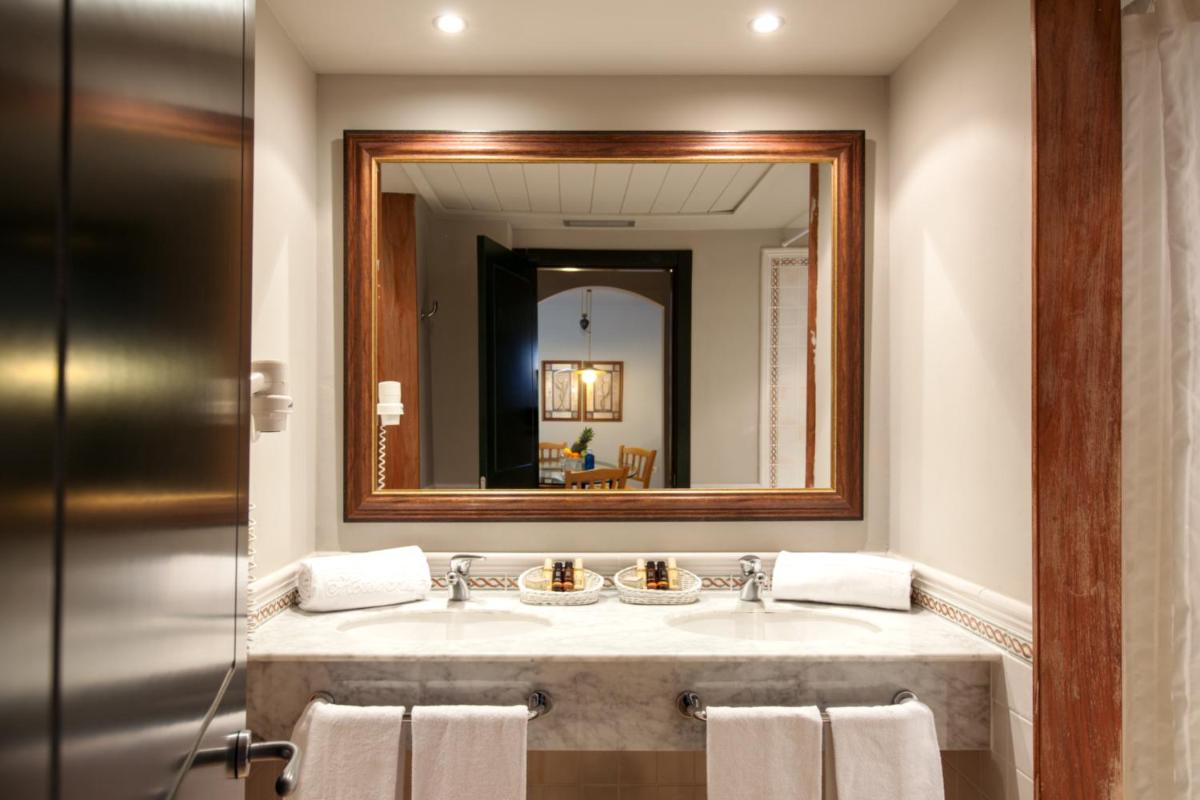 un baño con lavabo y espejo en Apartahotel Suites Vila Birdie, en Navata