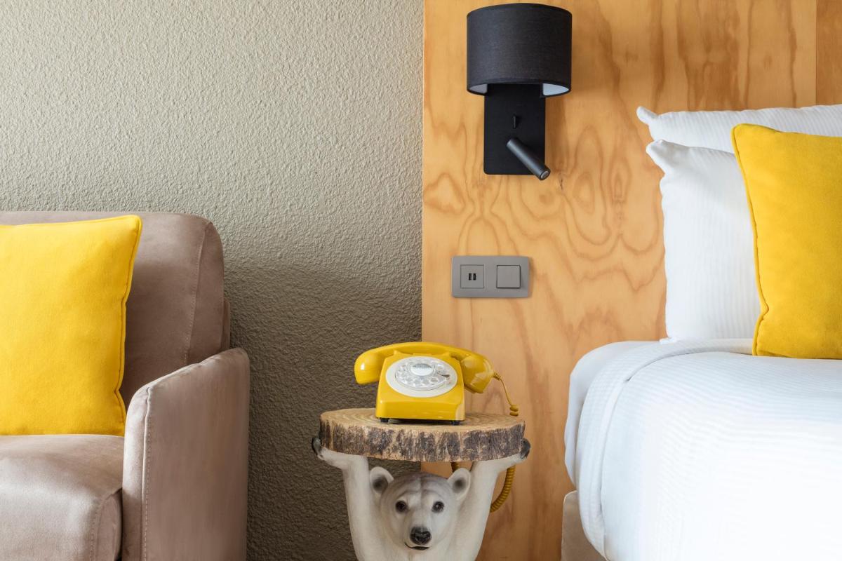 une chambre avec un lit et un téléphone jaune sur une table d'appoint dans l'établissement Hôtel Les Aiglons Chamonix, à Chamonix-Mont-Blanc 72 autres photos