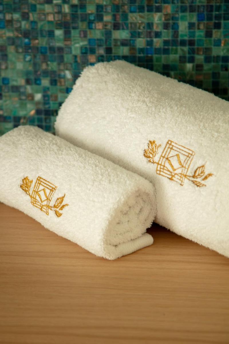 deux serviettes blanches avec broderies dorées sur un comptoir de salle de bain dans l'établissement Hôtel & Spa Villa Seren, à Hossegor